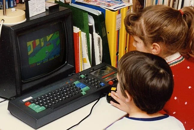 Niños que exploran en una computadora Amstrad CPC 464 en los años 80
