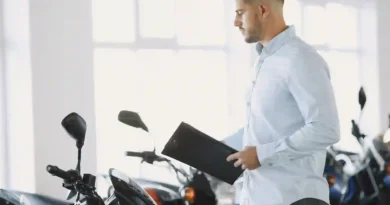 Vendedor con carpeta revisa motocicletas nuevas en el piso de ventas de un concesionario